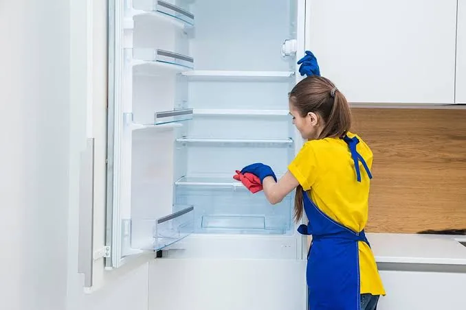 Cleaning inside the fridge during an Airbnb turnover in Raleigh, NC