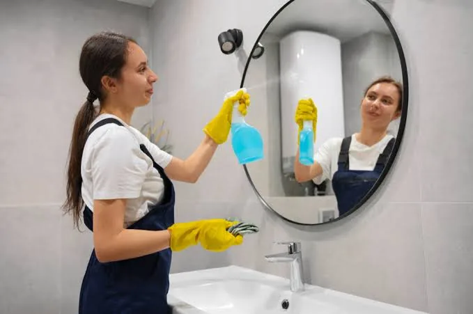 Cleaning the bathroom mirror during a deep clean in Raleigh, NC