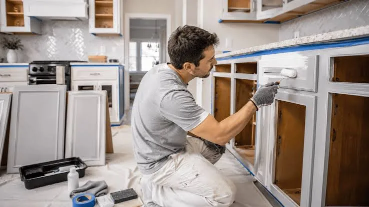 Painter priming kitchen cabinet frames with doors removed in Cary, NC